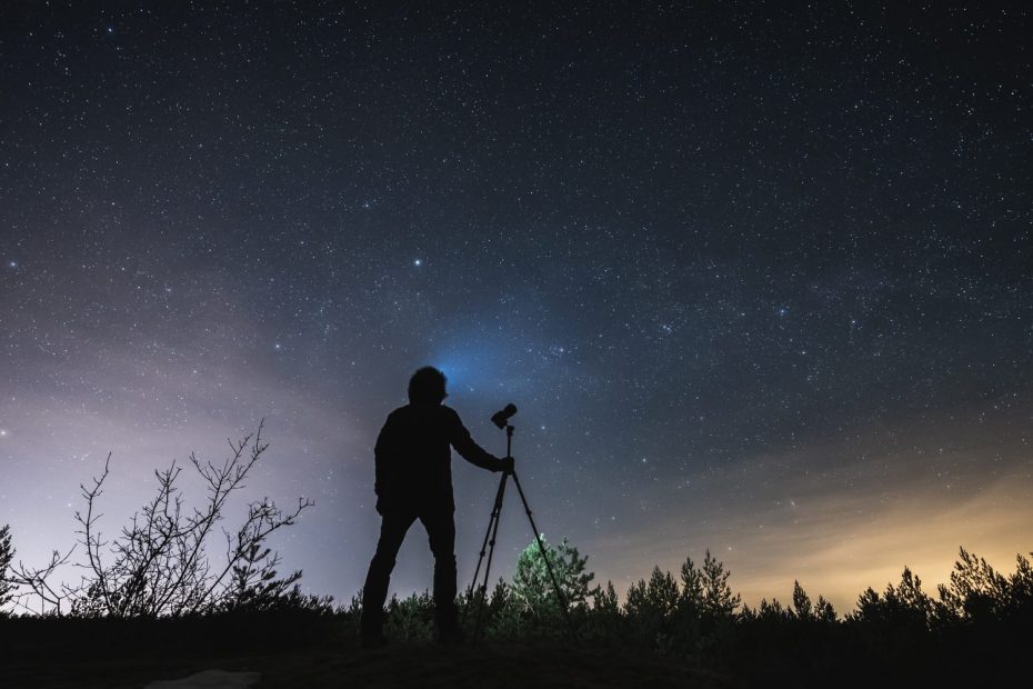Un débutant en astrophotographie photographie la Voie lactée avec un appareil photo installé sur un trépied.
