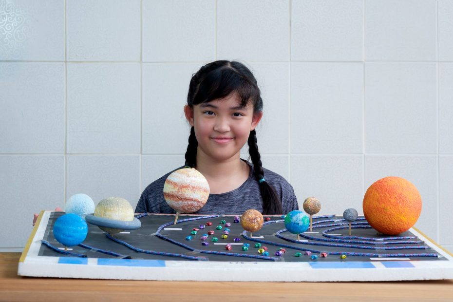 Un enfant observe une maquette colorée du système solaire avec les planètes disposées autour du Soleil.