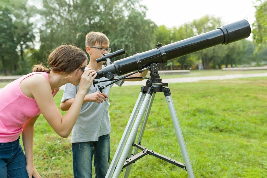 Débutant observant le ciel étoilé avec son premier télescope installé dans un jardin.