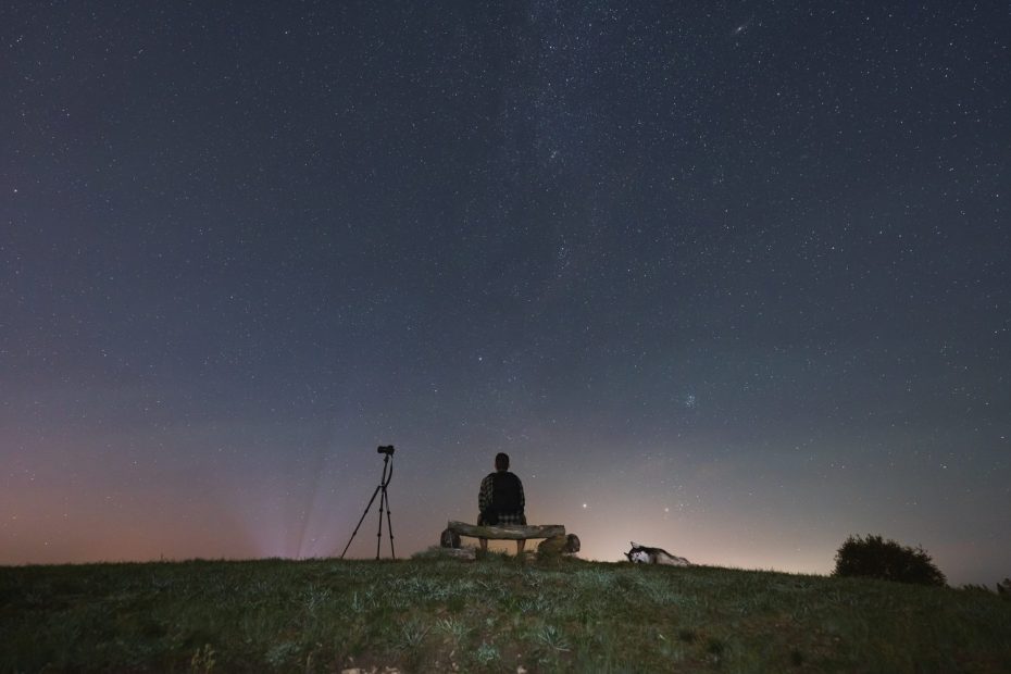 Amateur d’astrophotographie installant un appareil photo sur trépied sous un ciel étoilé.