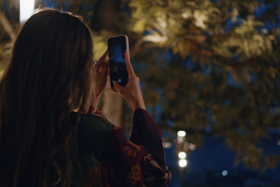 Une personne photographie un ciel étoilé avec son téléphone posé sur un trépied.