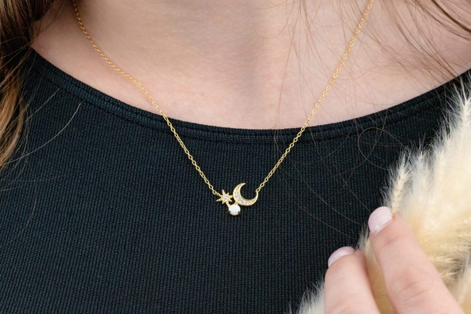 Gros plan sur un pendentif en forme de lune posé sur un tissu clair.