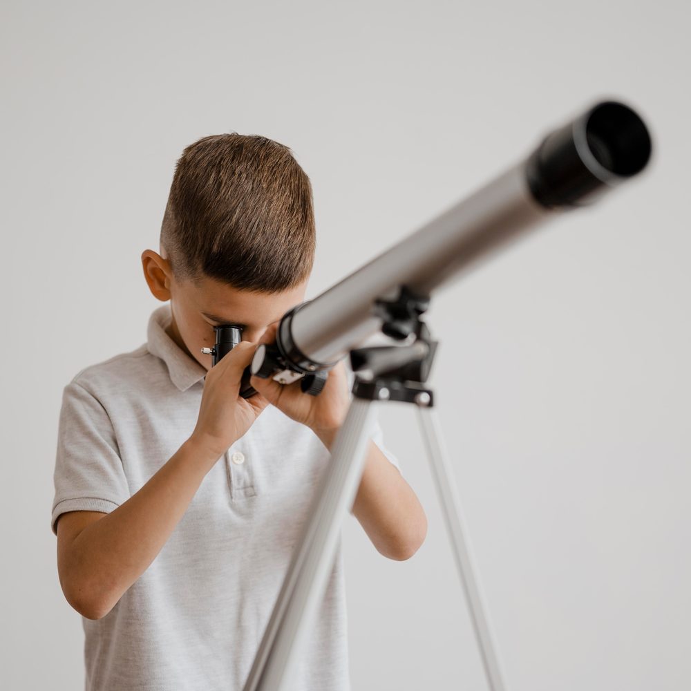 Une personne utilise un télescope d’entrée de gamme pour observer les étoiles depuis un jardin.