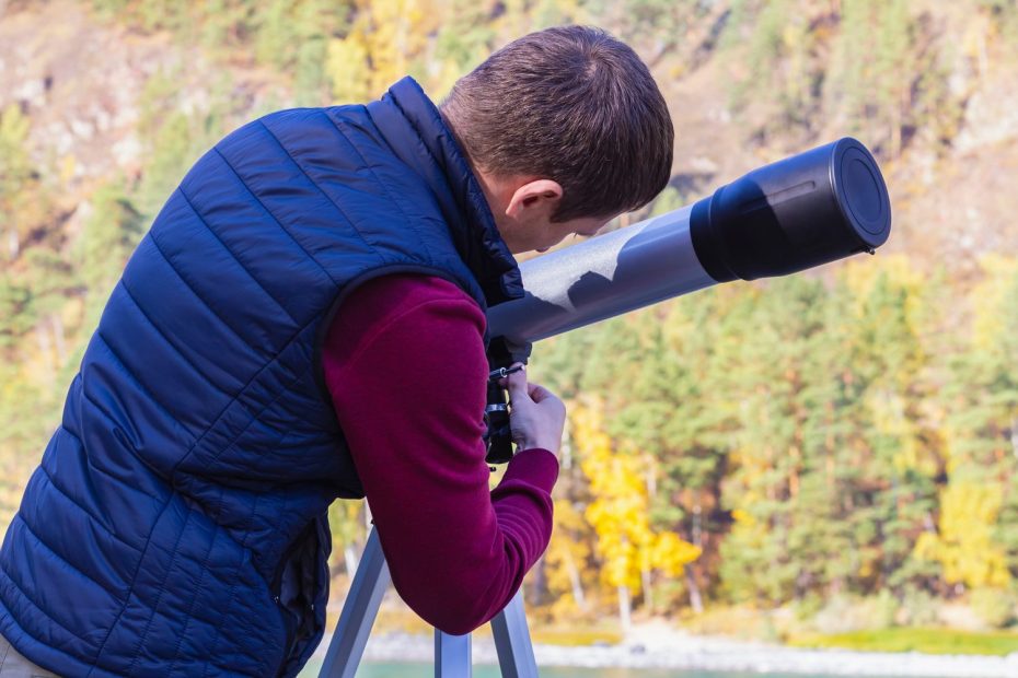 Un débutant observe le ciel nocturne avec un télescope installé sur un trépied.